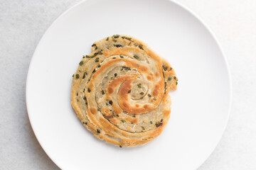 Overhead view of chinese scallion pancakes on a white plate, top view of golden-brown homemade scallion pancakes, process of making cong you bing