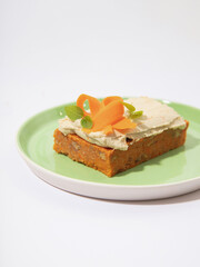 Carrot Cake with Cream Cheese Frosting and Carrot Garnish. A close-up shot of a slice of carrot cake topped with smooth cream cheese frosting, garnished with delicate carrot ribbons and fresh herbs