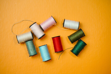 Spool of colorful sewing threads on orange background