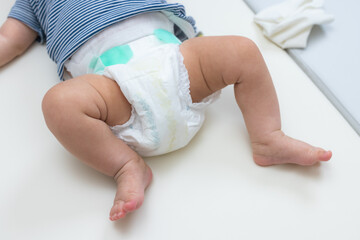 Closeup of baby legs with diaper on mat