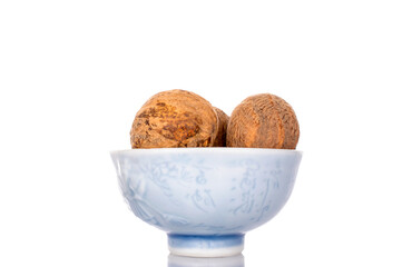 Several nutmegs on a ceramic saucer, close-up, isolated on a white background.