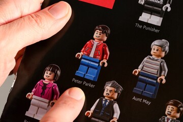 Naklejka premium Tambov, Russian Federation - January 02, 2025 Woman fingers pointing out Lego Peter Parker minifigure on a Lego Marvel cardboard box