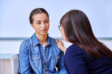 Female psychologist talking with teenage girl inside educational building
