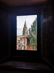 The view through a window in Toledo. Looking out through a wooden framed window at the medieval city of Toledo, Spain. Ancient architecture of the city is visible in the brightly lit window.