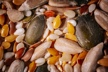 A vibrant close-up of a seed mix featuring pumpkin seeds, flaxseeds, sesame seeds, and sunflower seeds. The colorful textures highlight the variety and freshness of the seeds.