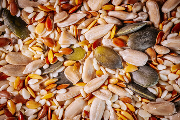 A vibrant close-up of a seed mix featuring pumpkin seeds, flaxseeds, sesame seeds, and sunflower seeds. The colorful textures highlight the variety and freshness of the seeds.