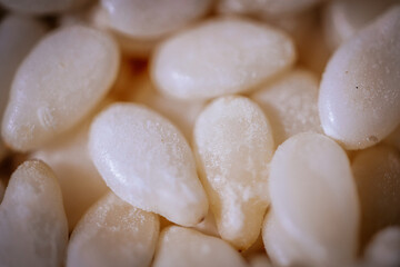 A macro shot of white sesame seeds showcasing their smooth texture and oval shape, commonly used in...