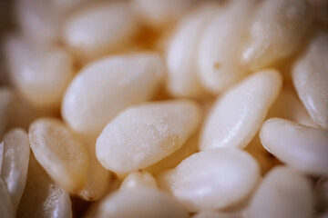 A macro shot of white sesame seeds showcasing their smooth texture and oval shape, commonly used in...