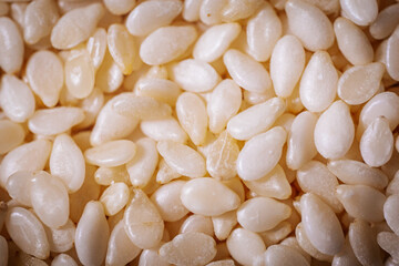 A macro shot of white sesame seeds showcasing their smooth texture and oval shape, commonly used in...