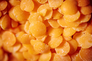 A close-up view of vibrant orange lentils, highlighting their smooth, flat texture and natural color. Ideal for showcasing healthy, plant-based food options.