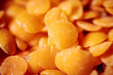 A close-up view of vibrant orange lentils, highlighting their smooth, flat texture and natural color. Ideal for showcasing healthy, plant-based food options.