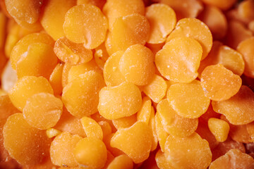 A close-up view of vibrant orange lentils, highlighting their smooth, flat texture and natural color. Ideal for showcasing healthy, plant-based food options.