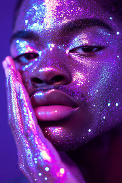 Fototapeta A close-up portrait of a person with their hand gently touching their face, covered in dazzling purple glitter, with sparkling glitter on the skin and around the eyes.  