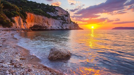 Obraz premium Serene Sunset Cove: A picturesque coastal scene at sunset, featuring a tranquil beach, dramatic cliffs, and the warm glow of the setting sun reflecting on the calm sea. 