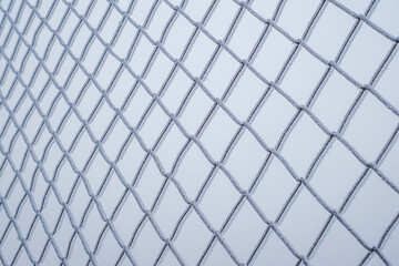 Fototapeta premium Looking through frozen wire fence covered with ice