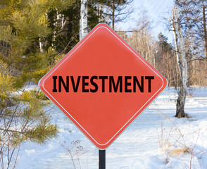 Investment symbol. Concept word Investment on beautiful red road sign. Beautiful winter snow forest background. Business investment concept. Copy space.