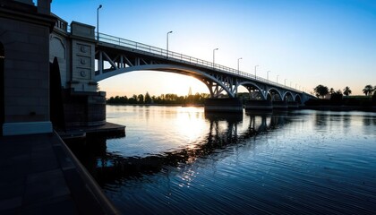 Fototapeta premium Sunrise over river bridge, calm waters. Possible use stock photo