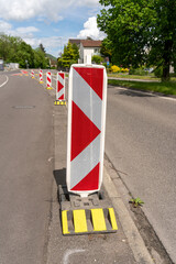 Row of reflective traffic diversion signs in red and white with yellow stands. Daytime scene, under...