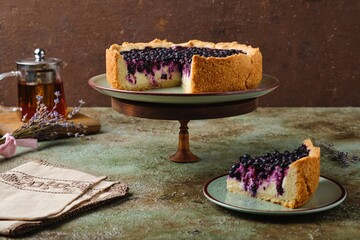 Round pie on shortcrust pastry with sweet curd filling and berries on a ceramic green plate on a green concrete background. Baking with cottage cheese.