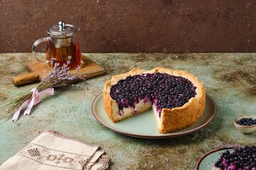 Round pie on shortcrust pastry with sweet curd filling and berries on a ceramic green plate on a green concrete background. Baking with cottage cheese.