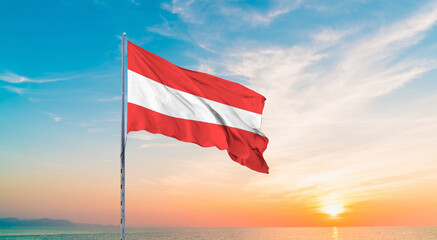 Waving flag of Austria against the background of a sunset or sunrise. Austria sky with flying flag beauty.  Concept of national holidays. Austria flag for Independence , Commemoration Day.