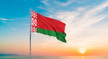 Waving flag of Belarus against the background of a sunset or sunrise. Belarus sky with flying flag...