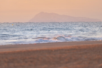 Fototapeta premium Waves on the beach. Sunrise on the beach. A nice sunrise. Lights and reflections of sunrise on a beautiful beach - Mediterranean Sea coastal tsunami warning