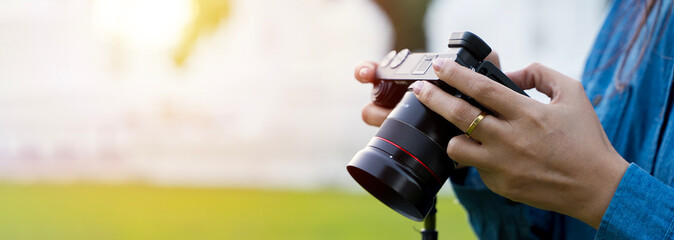 Person holds action camera with microphone by special handle, and with other hand adjusts display to see subject.