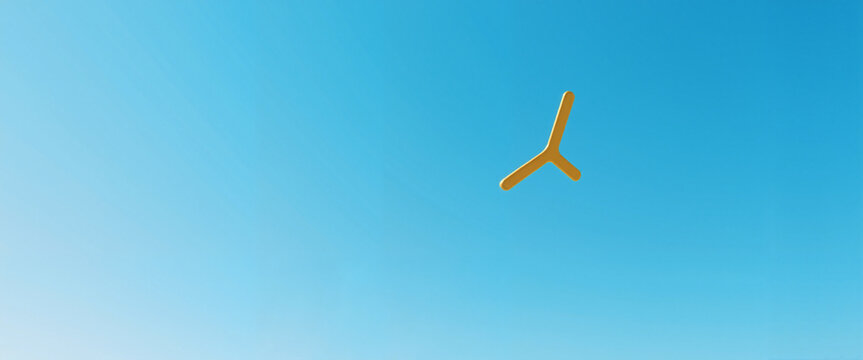 Yellow boomerang flying in clear blue sky