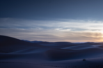 Beautiful panorama of the dusk in the Sahara desert in Morocco. The sun has set and the dunes form soft contrasts of light and shadow. The image inspires the cold of the desert night © LaMorenita