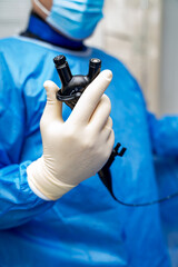 Doc uses endoscope for exam. A healthcare worker in blue scrubs prepares an endoscope, readying for...