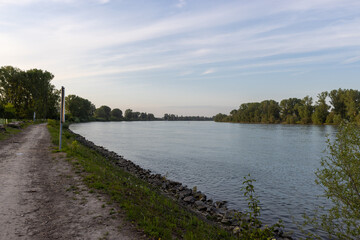 A peaceful riverside scene with a dirt path running alongside the calm river.