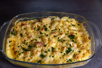 A delicious potato, asparagus, and ham casserole topped with melted cheese and garnished with fresh parsley, baked to perfection.