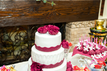 Rose-adorned wedding cake. A three-tier wedding cake showcases intricate details and beautiful rose...