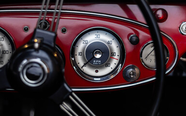 Close-up of a vintage car dashboard featuring an RPM gauge, fuel gauge, and chrome details on a...