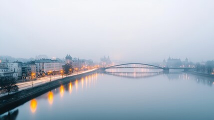 Obraz premium Serene Cityscape at Dawn with Misty River and Illuminated Bridge Alongside Urban Architecture