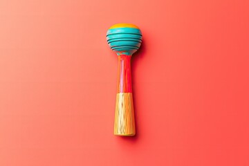 brightly painted wooden noisemaker placed in center of solid coral background with subtle gradients