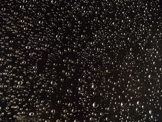 Abstract Water Droplets on Black: A captivating close-up of water droplets scattered across a black surface, creating a mesmerizing abstract pattern. The droplets shimmer with subtle reflections.