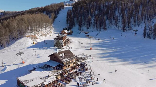 Aerial of ski slope lunch restaurants and lift Sauze d'Oulx Vialattea Italy in clear sunshine blue sky