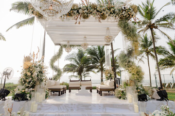 A romantic white beach wedding celebration with an outdoor ceremony, featuring elegant decor, a bottle for colored sand rituals, and a beautifully arranged table under the open sky