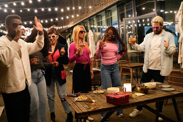 Multiethnic friends enjoying drinks and dancing at rooftop party