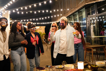 Multiethnic friends enjoying rooftop party with food, drinks, and dancing