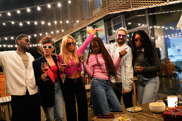 Multiethnic friends enjoying rooftop party with drinks and dancing