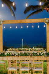 A romantic white beach wedding celebration with an outdoor ceremony, featuring elegant decor, a bottle for colored sand rituals, and a beautifully arranged table under the open sky