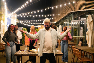 Friends dancing under string lights at rooftop party