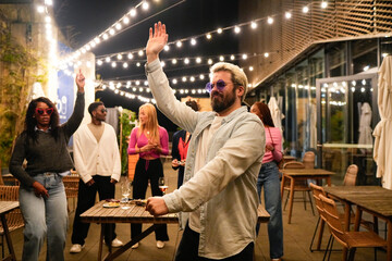 Multiethnic friends dancing and enjoying rooftop party