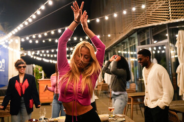 Young woman dancing with friends at rooftop party
