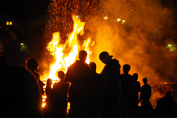 Sonnwendfeuer mit Menschen im Vordergrund.