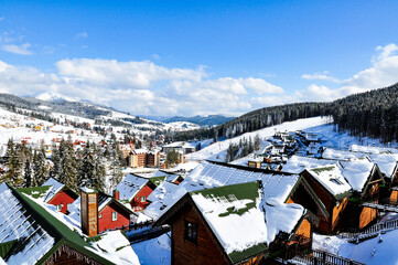 A view from above of a snow-covered winter village, harmoniously integrated into the mountain...