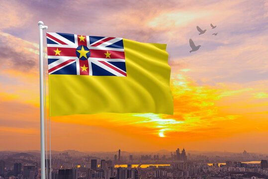 Waving flag of Niue against the background of a sunset or sunrise. Niue national flag for independence day. Concept of national holidays. Niue sky with flying flag beauty.